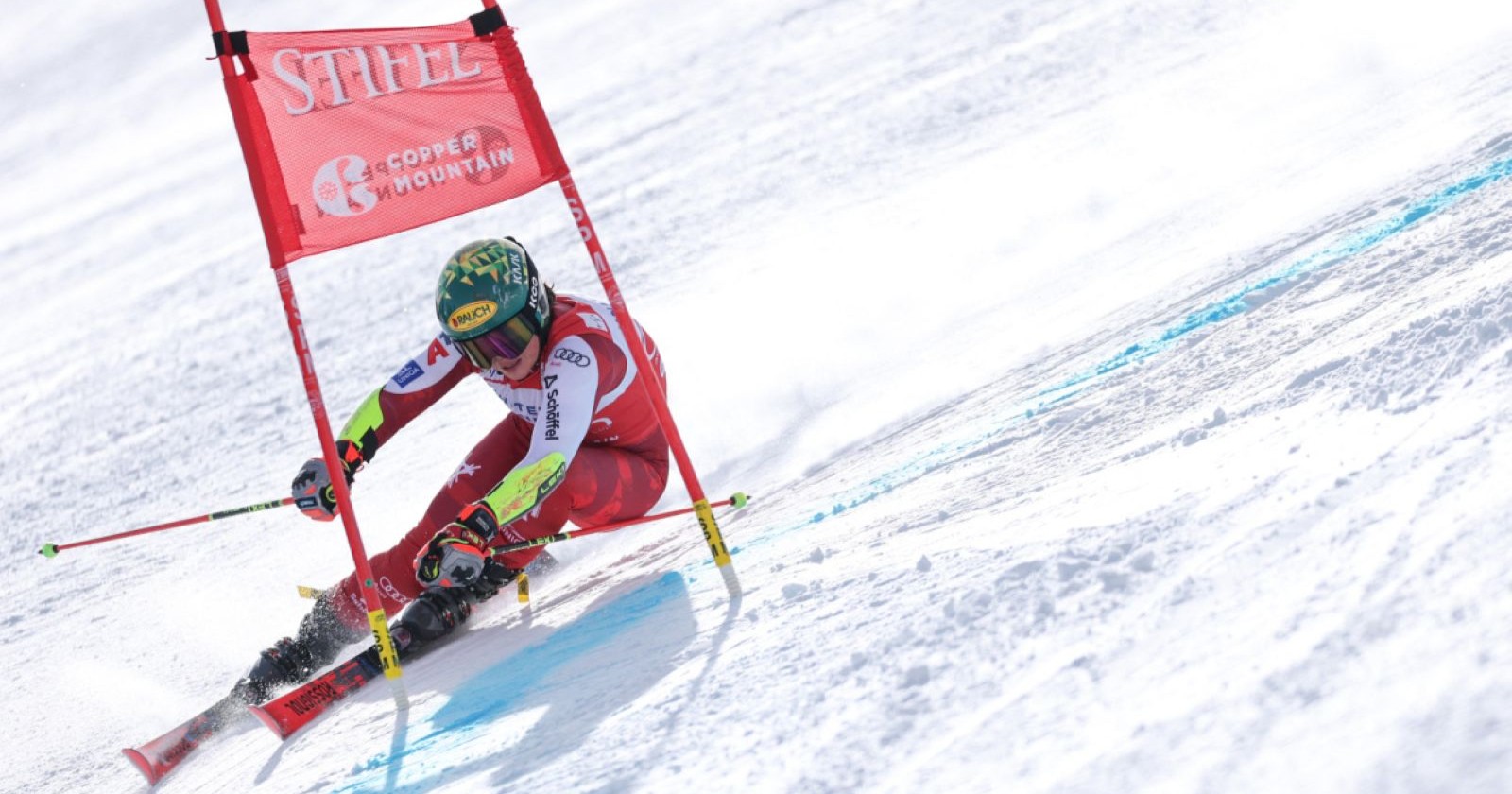 Skirennläuferin in voller Rennposition fährt im Riesentorlauf von Copper Mountain durch ein Tor auf verschneiter Strecke.