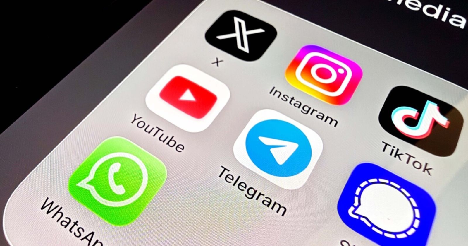 Nahaufnahme eines Smartphone-Bildschirms mit verschiedenen Social-Media-App-Symbolen, darunter X, Instagram, TikTok, YouTube, Telegram, WhatsApp und Signal.