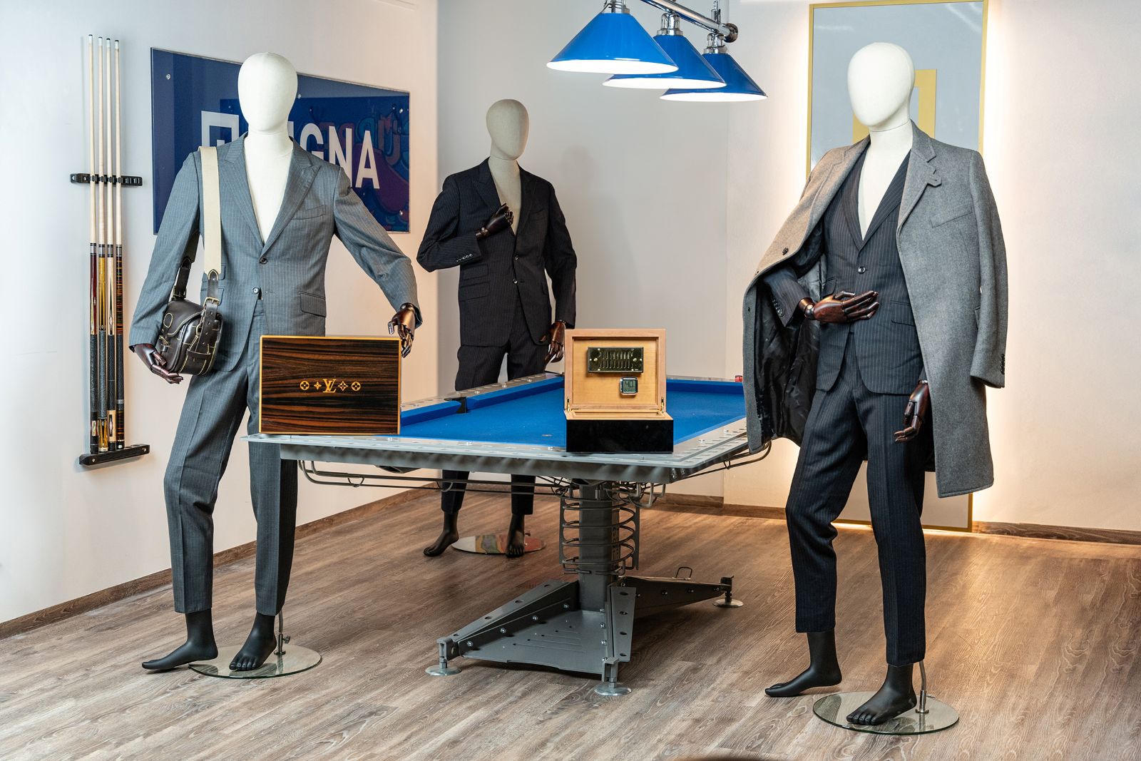 Drei Schaufensterpuppen mit Benko-Anzügen, Mänteln und Zigarrenhumidoren von Louis Vuitton, ausgestellt auf einem Billardtisch im Rahmen der Aurena-Auktion.