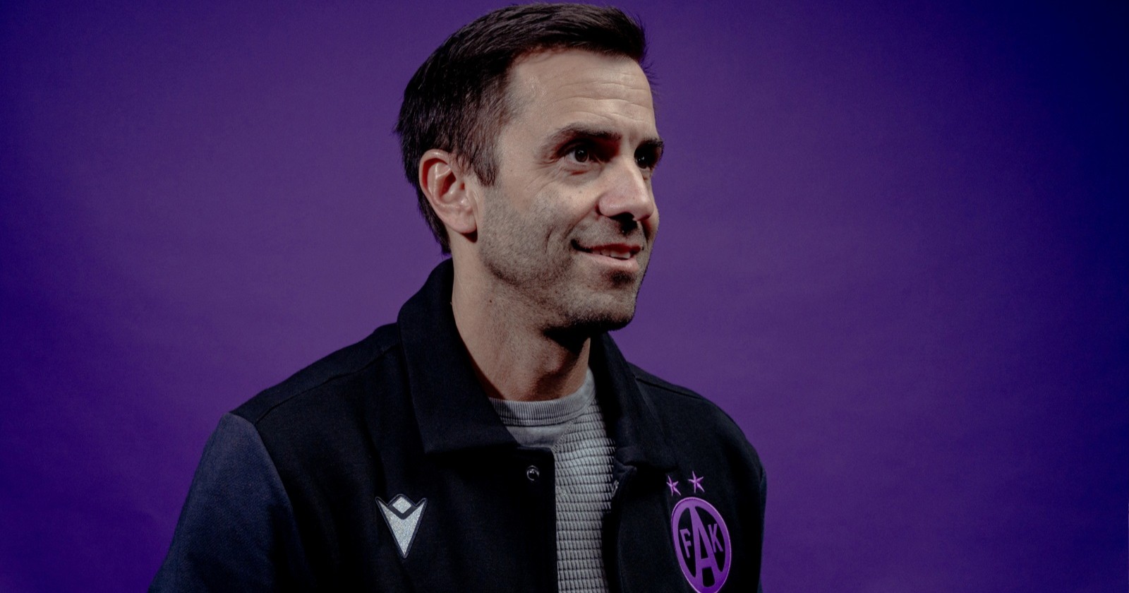 Michael Wagner in College-Jacke von Austria Wien vor violettem Hintergrund
