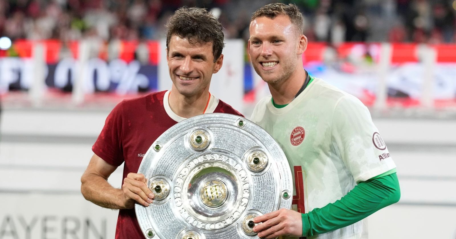 Thomas Müller und Daniel Peretz posieren mit der Meisterschale im Trikot des FC Bayern München