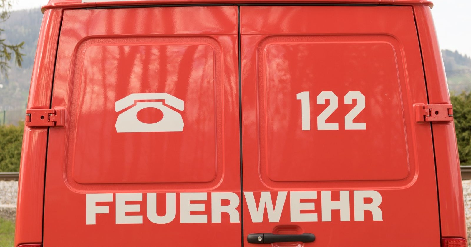 Rückseite eines roten Feuerwehrfahrzeugs mit der Notrufnummer 122.