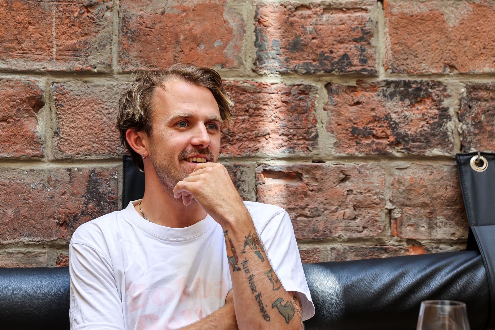 Ein junger Mann in weißem Shirt blickt nachdenklich drein