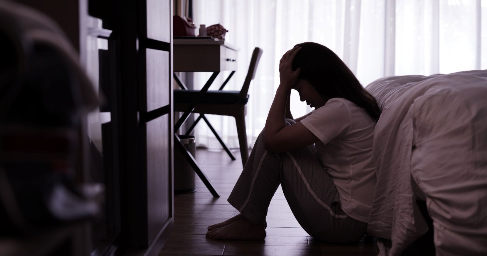 Frau sitzt traurig am Boden