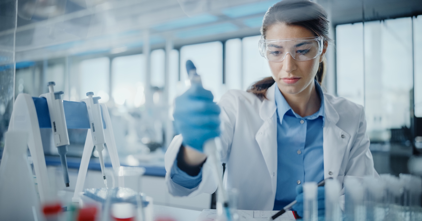 Frau im Labor mit weißen Kittel hantiert mit Pipette