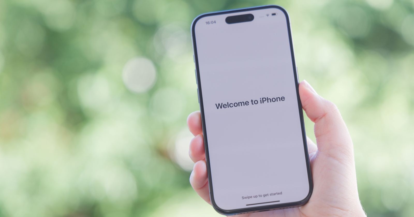 Ein Apple iPhone 15 Pro Smartphone in der Vorderansicht mit der standardisieren Begrüßungsnachricht in der Farbvariante Space Black.