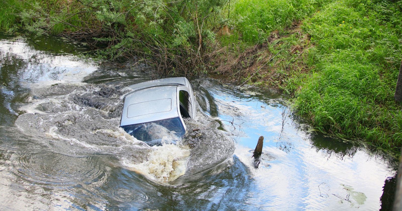 Silbernes Auto, welches in einen Fluss gestürzt ist