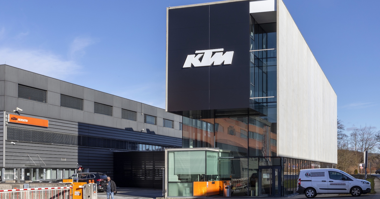 Moderne Gebäudefassade des KTM-Stammwerks in Mattighofen mit großem KTM-Logo, aufgenommen bei Sonnenschein
