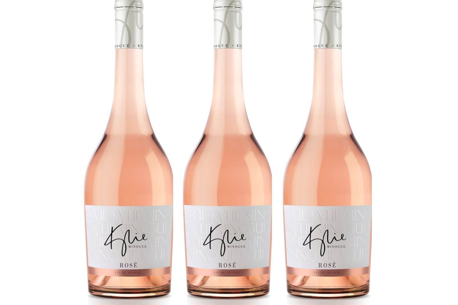 Drei roséfarbene Weinflaschen der Marke Kylie Minogue Rosé stehen nebeneinander vor weißem Hintergrund.