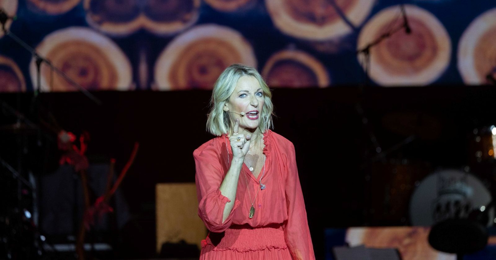 Monika Gruber in rotem Kleid auf der Bühne.