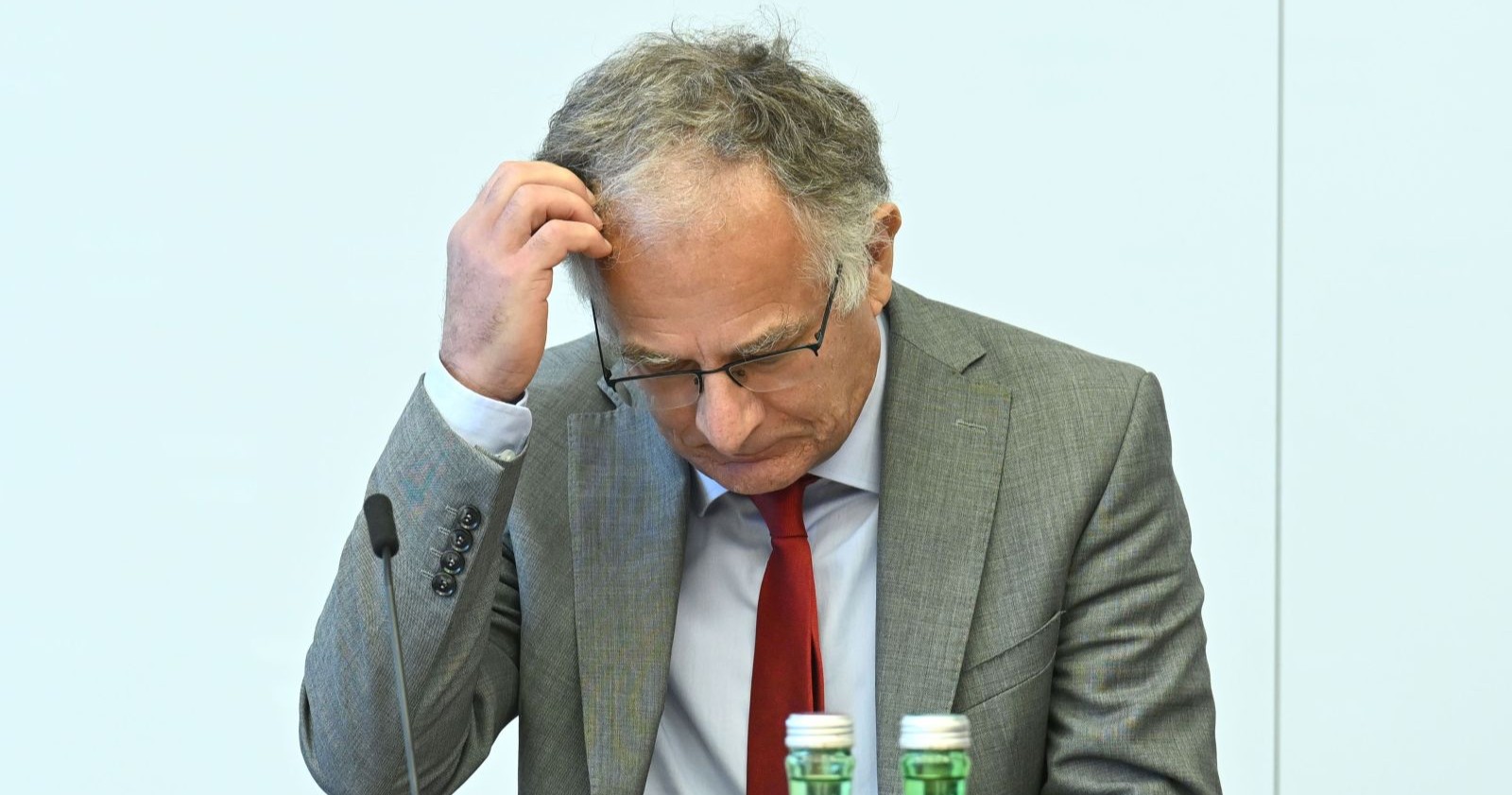 Finanzminister Marterbauer im grauen Anzug und roter Krawatte blickt nachdenklich nach unten, während er sich an den Kopf fasst – Symbolbild zur Budgetkrise in Österreich.