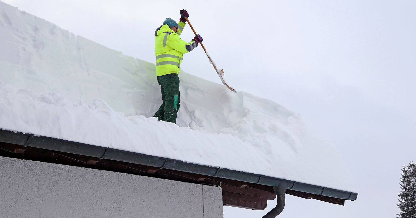 Mann schaufelt Schnee vom Dach | Credit: iStock.com/Astrid860