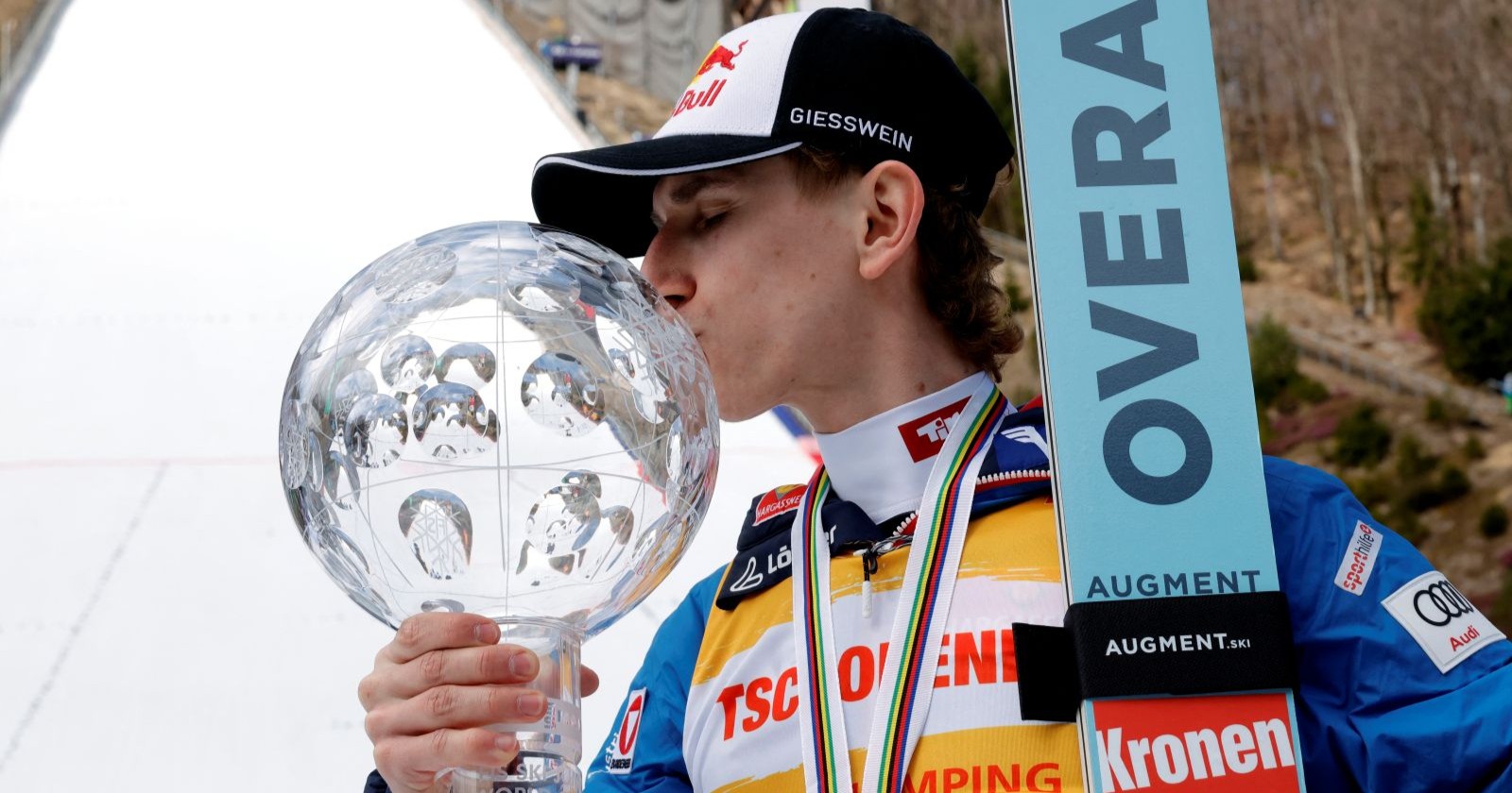 Daniel Tschofenig im Trikot des Gesamtweltcupführenden in Planica mit der Trophäe für den Gesamtweltcupsieg in Skispringen