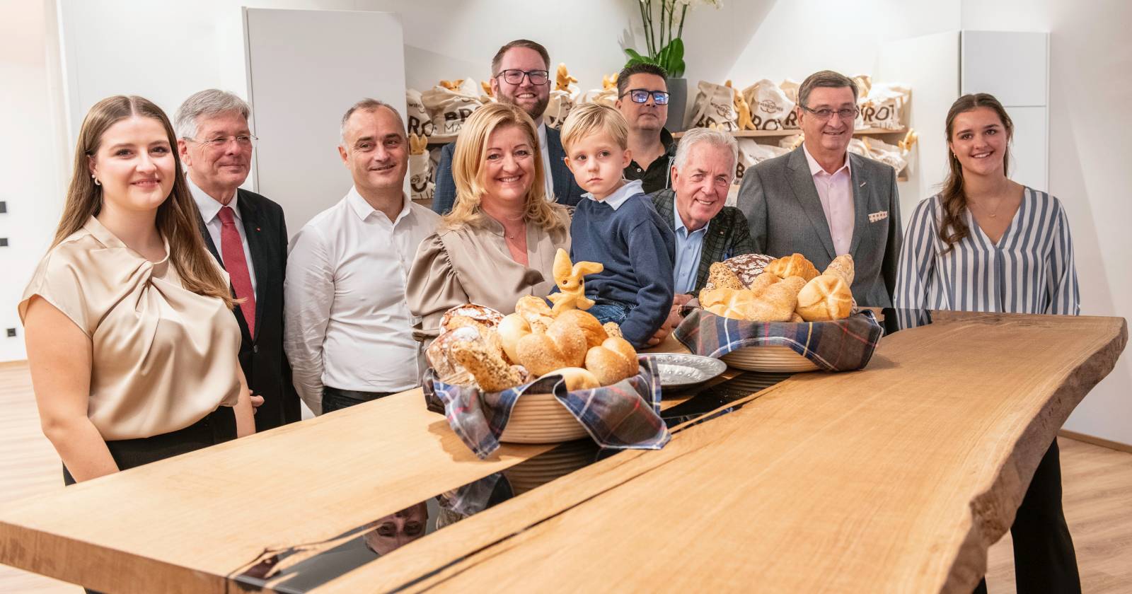 Die Familie Wienerroither, die gemeinsam mit LH Peter Kaiser und WK-Präsident Jürgen Mandl halbkreisförmig hinter einem großen Holztisch steht, auf dem sich zwei Körbe mit frischem Gebäck befinden