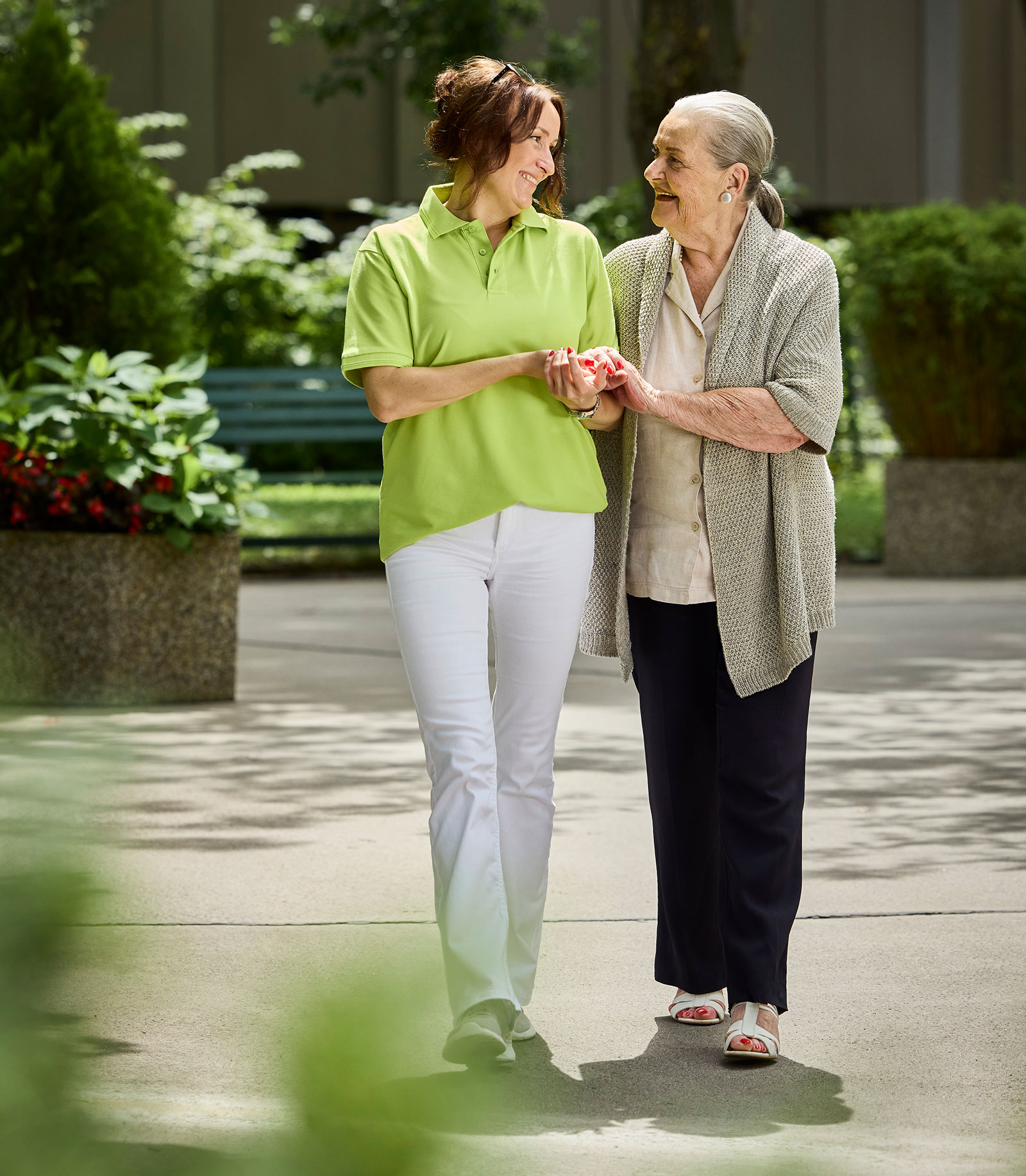 Seniorin geht gestützt auf eine weibliche Pflegekraft spazieren | Credit: Gerry Frank