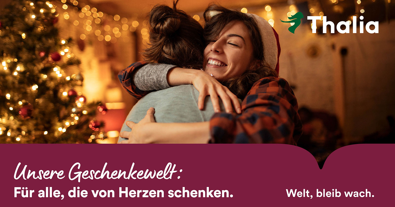 Frau umarmt gute Freundin vor dem Weihnachtsbaum | Credit: Thalia