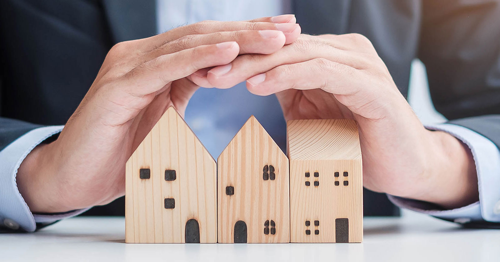 Ein Immobilientreuhänder mit einem Miniaturhaus | Credit: AdobeStock