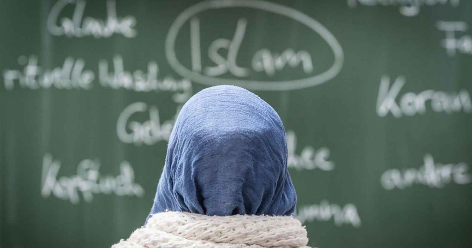 Mädchen mit Kopftuch vor einer Schultafel mit verschiedenen Wörtern