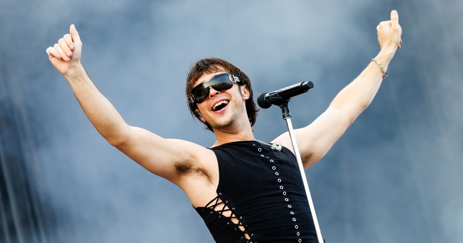 Ein Sänger mit Sonnenbrille tanzt vor einem Mikrofon