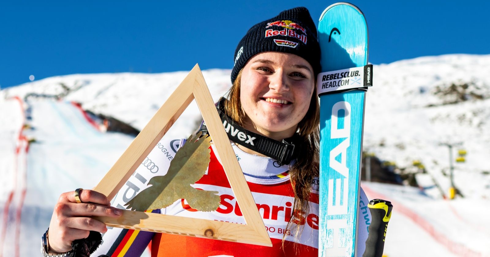 Junge Frau hält Ski und Trophäe in der Hand
