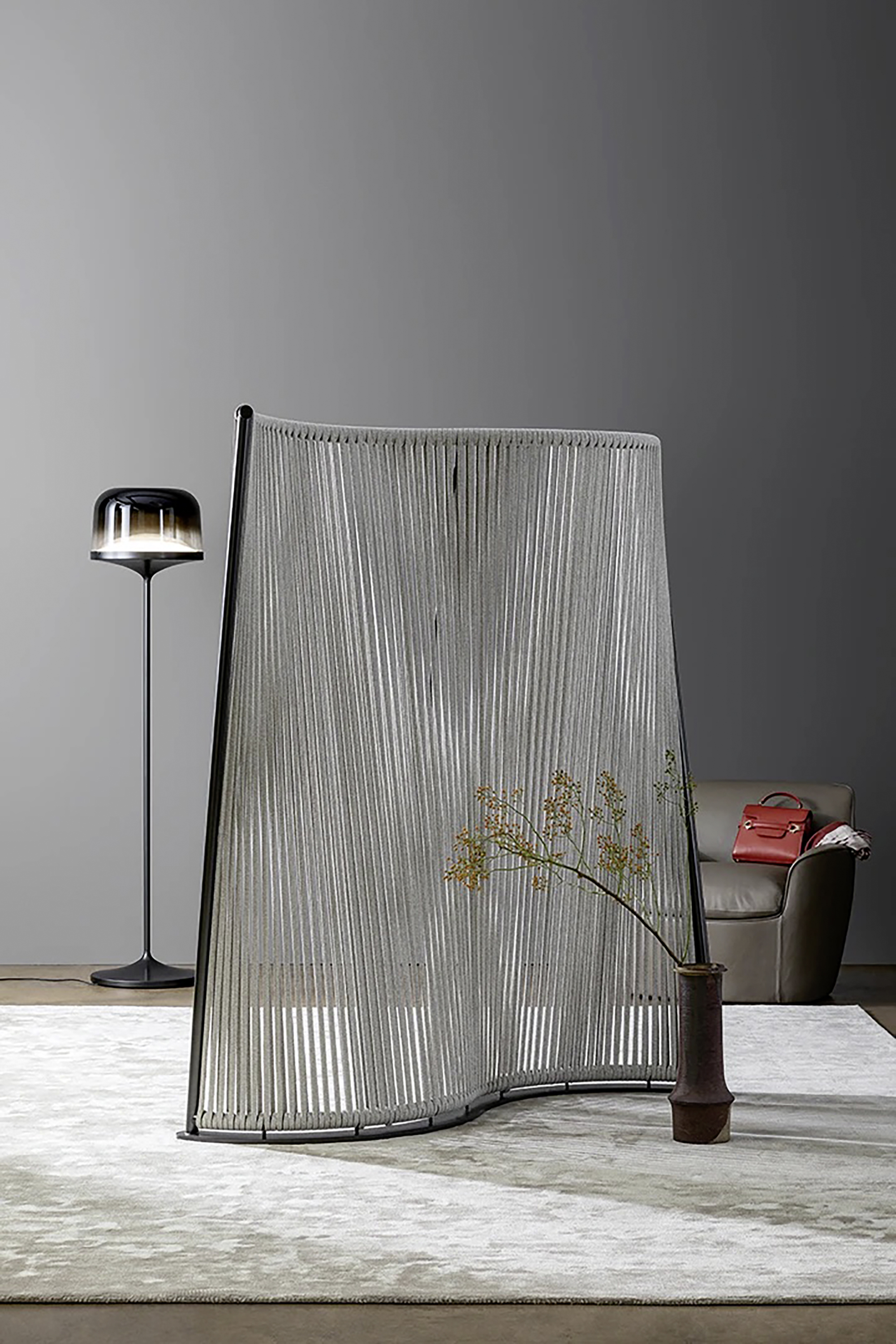 Silberner Paravent steht in einem Raum, dahinter ist eine Lampe zu sehen