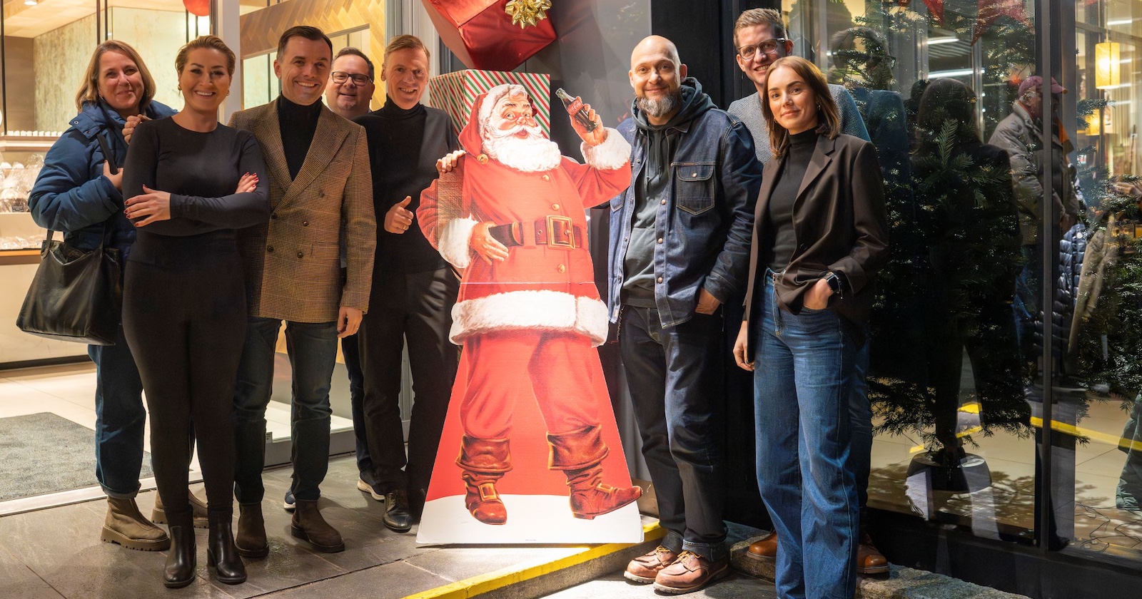 Menschengruppe mit Weihnachtsmann-Aufsteller vor einer DerMann-Filiale