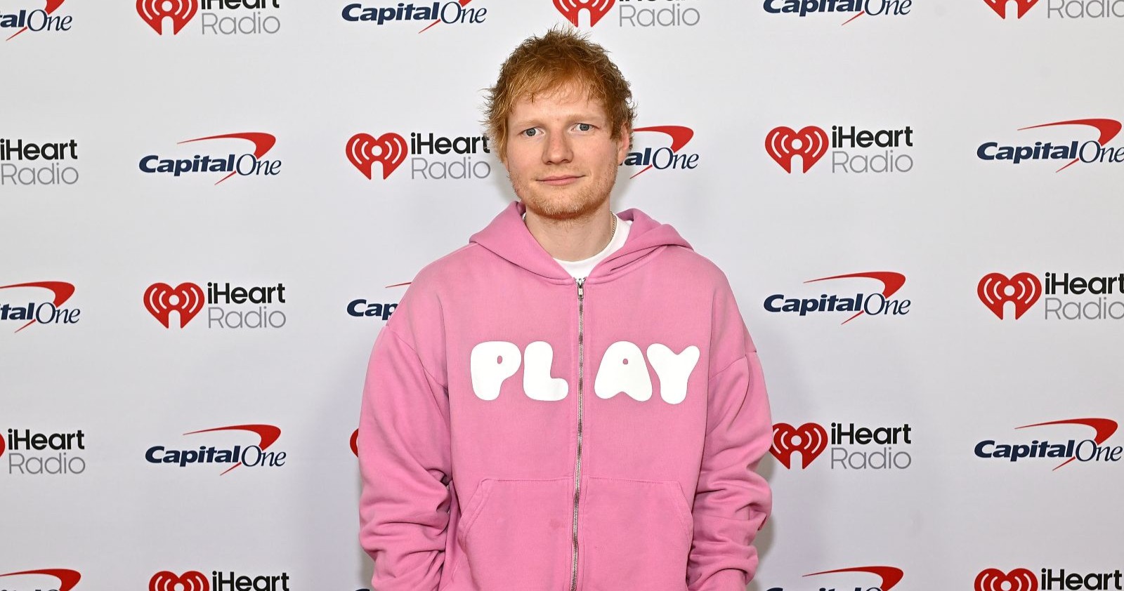 Ed Sheeran in einem rosa Pulli auf einer Veranstaltung.