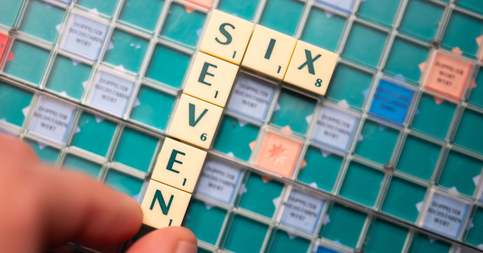 Scrabble-Spielbrett mit den Buchstaben „SIX“ und „SEVEN“, die das Jugendwort des Jahres 2025 darstellen.