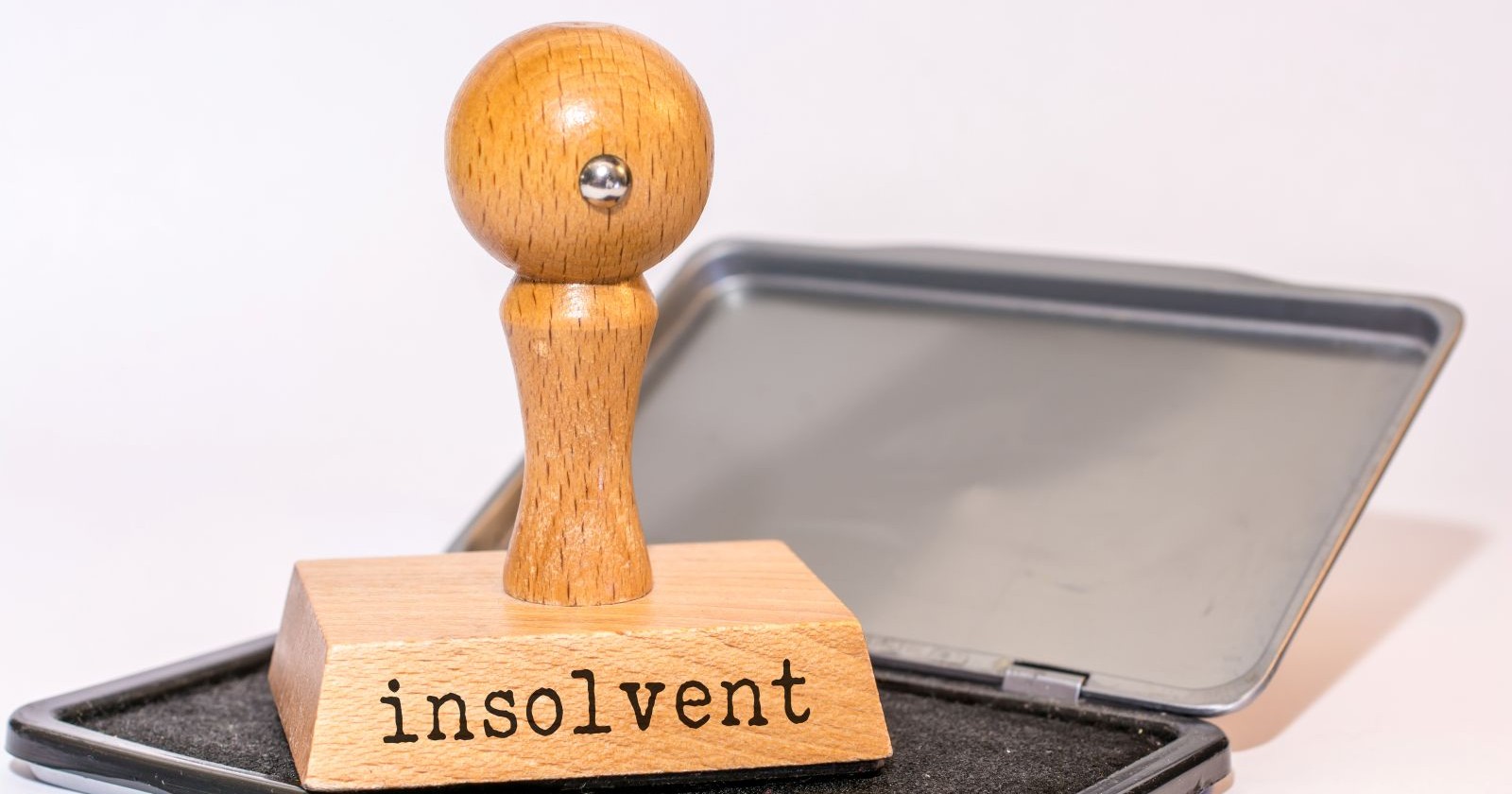 Stempel auf einem Stempelkissen, auf dem Stempel steht das Wort Insolvenz geschrieben