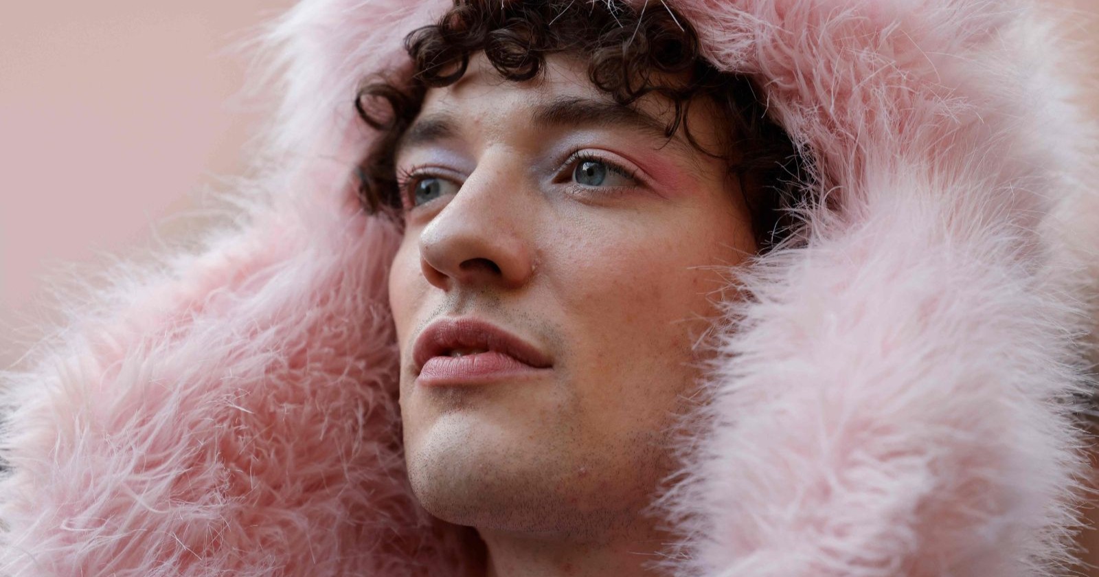 Nahaufnahme von Nemo in rosa Kunstpelzkapuze, leicht geschminkt, nachdenklicher Gesichtsausdruck.