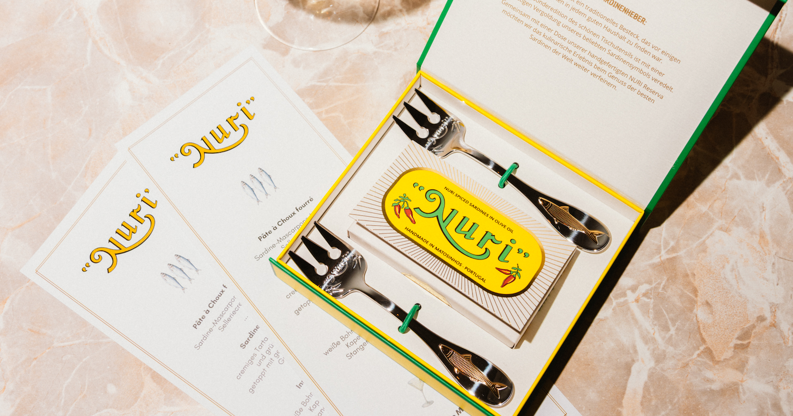 zwei vergoldete Sardinengabeln in einer Geschenkbox mit einer Dose Sadrinen