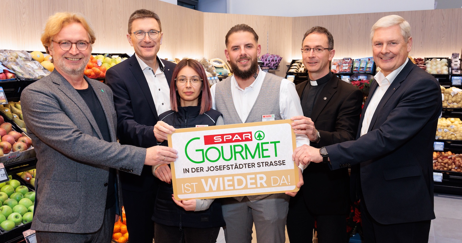 Sechs Personen halten in der Spar-Filiale ein Spar-Gourmet-Schild