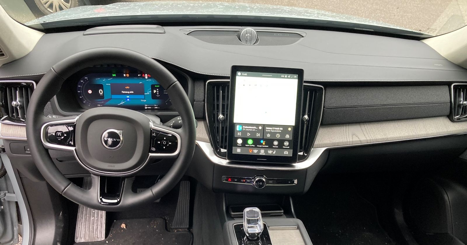 Das Armaturenbrett sowie das Lenkrad des Volvo XC90 sind in grau gehalten. Zu sehen ist auch ein Display in der Mitte des Fahrzeugs.