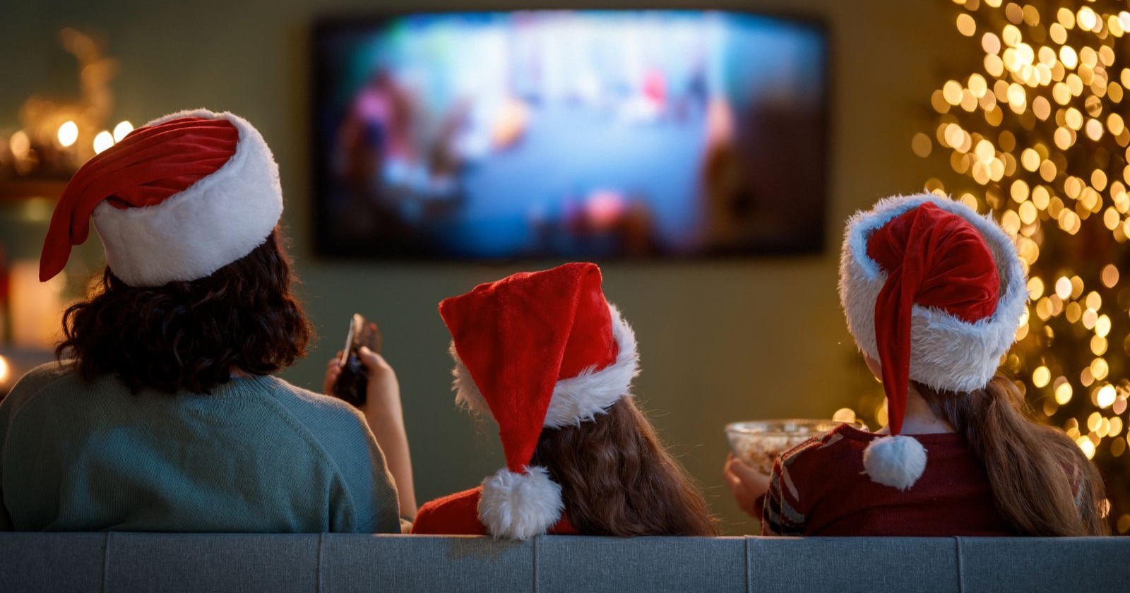 Drei Menschen mit Weihnachtsmütze sitzen auf einer Couch