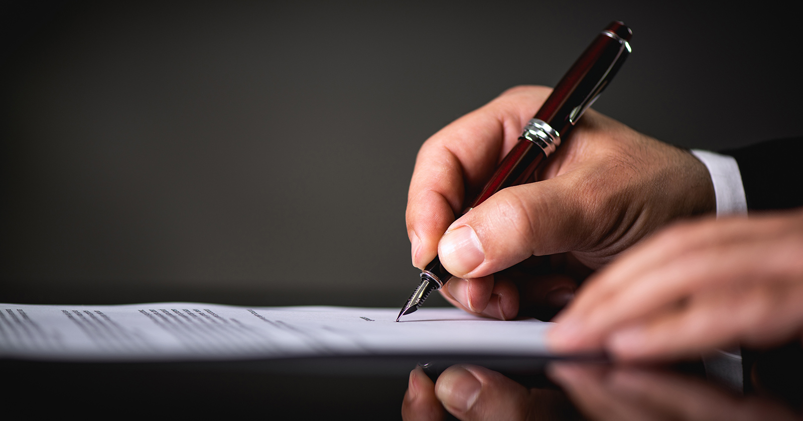 Mann bei der Unterzeichnung des Dokuments | Credit: iStock.com/ilkercelik