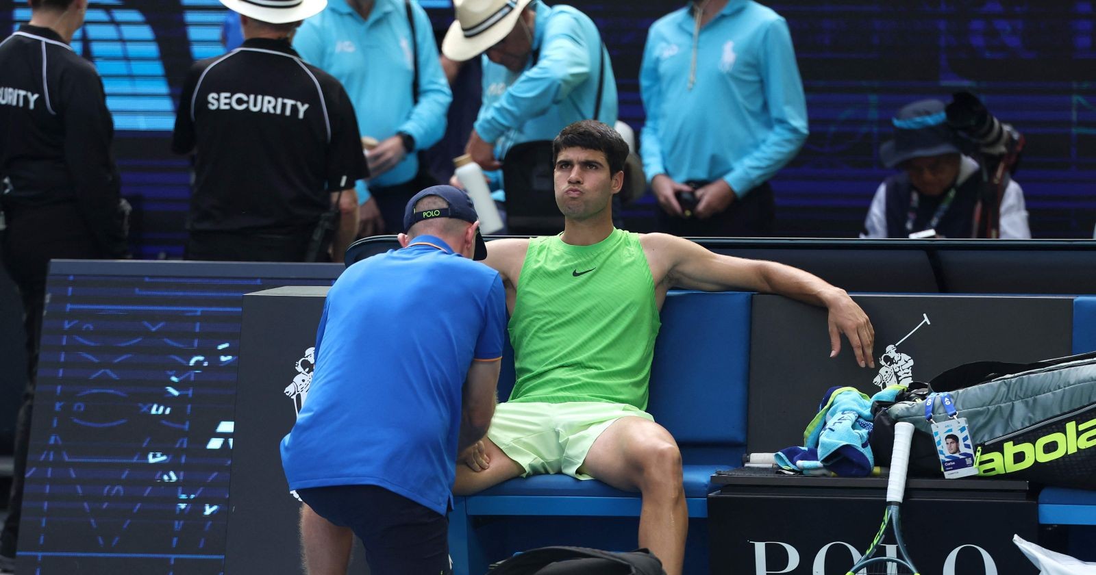 Carlos Alcaraz sitzt während einer medizinischen Unterbrechung bei den Australian Open auf der Bank und wird nach Krämpfen behandelt.