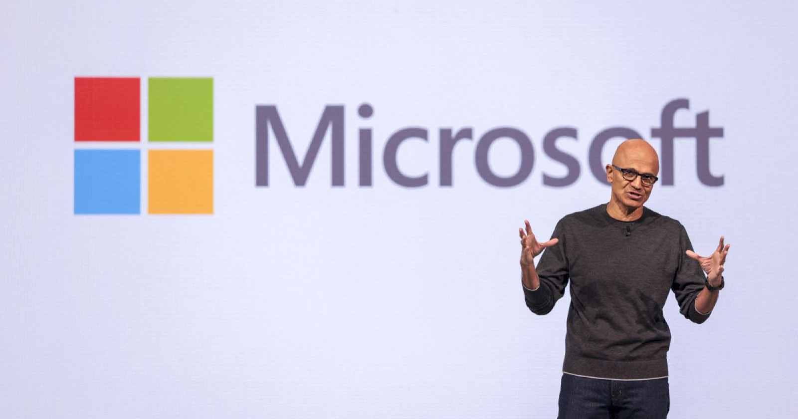 Microsoft-CEO spricht auf einer Bühne vor dem Firmenlogo während einer Präsentation.