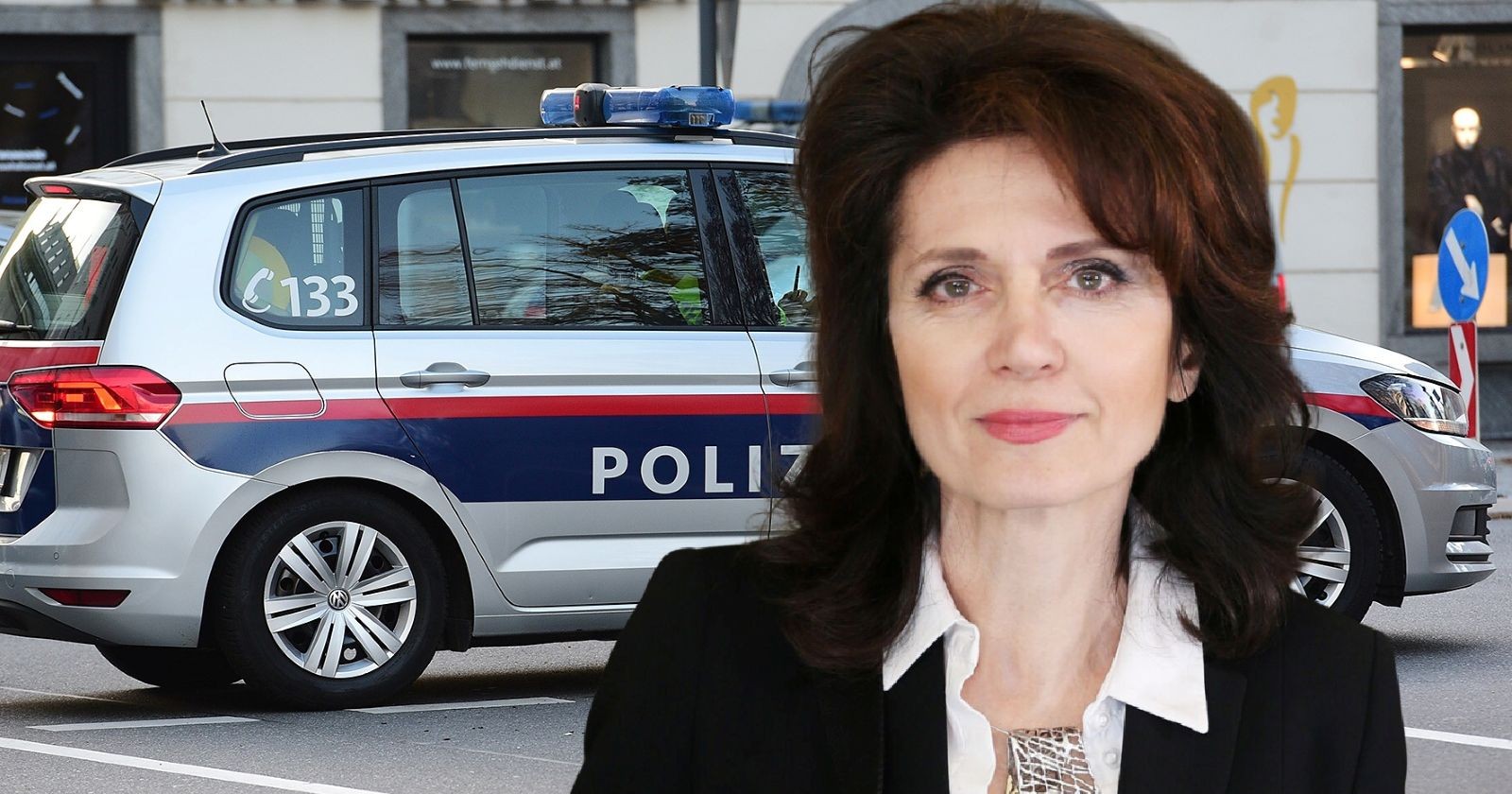 Astrid Wagner in schwarzem Blazer und weißer Bluse steht vor einem österreichischen Polizeifahrzeug mit der Aufschrift „Polizei“.