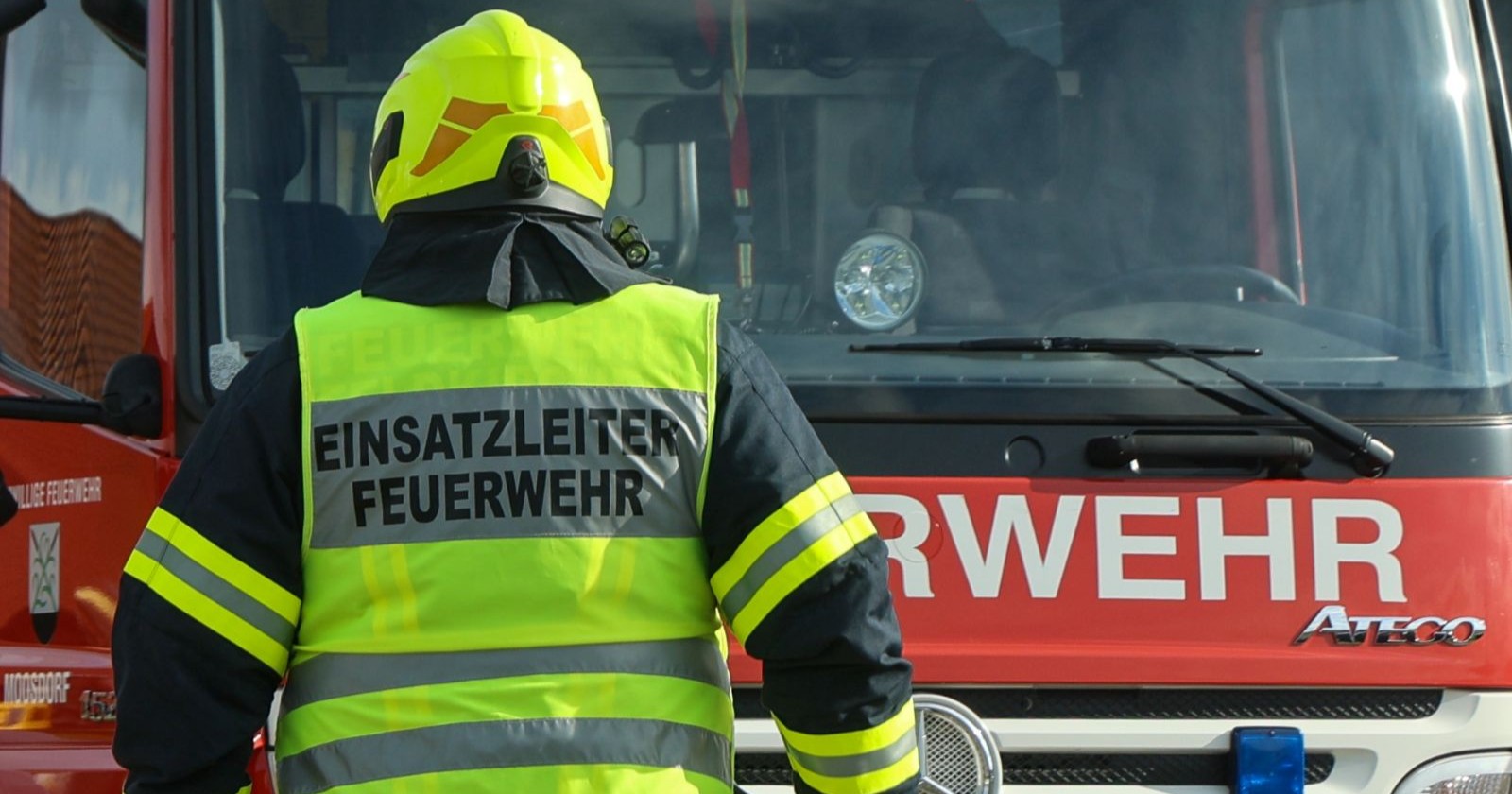 Einsatzleiter der Feuerwehr steht vor dem Feuerwehrauto
