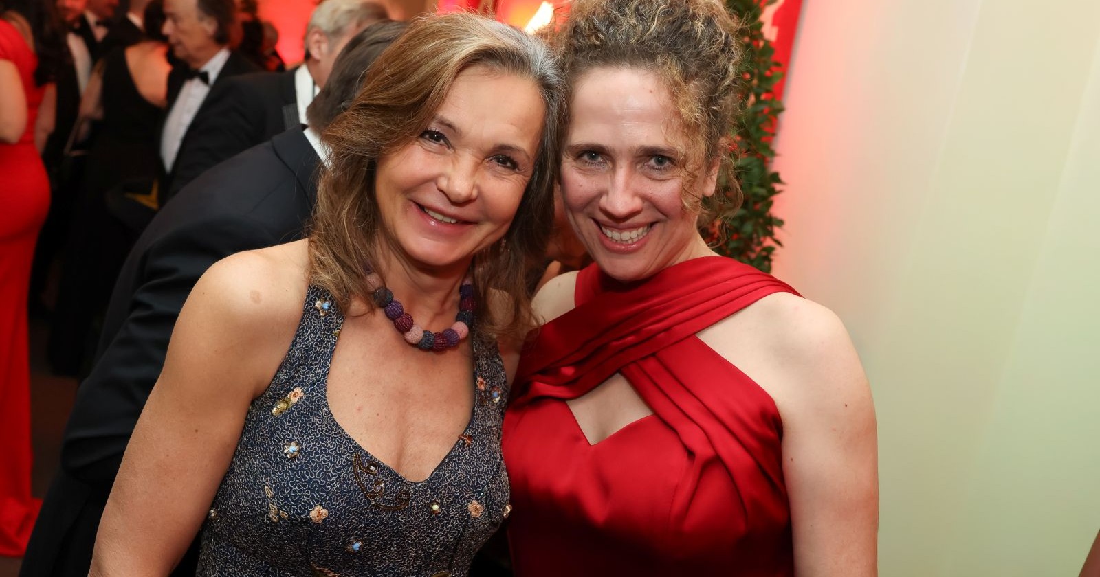 Zwei lachende Damen stecken am Ball die Köpfe zusammen