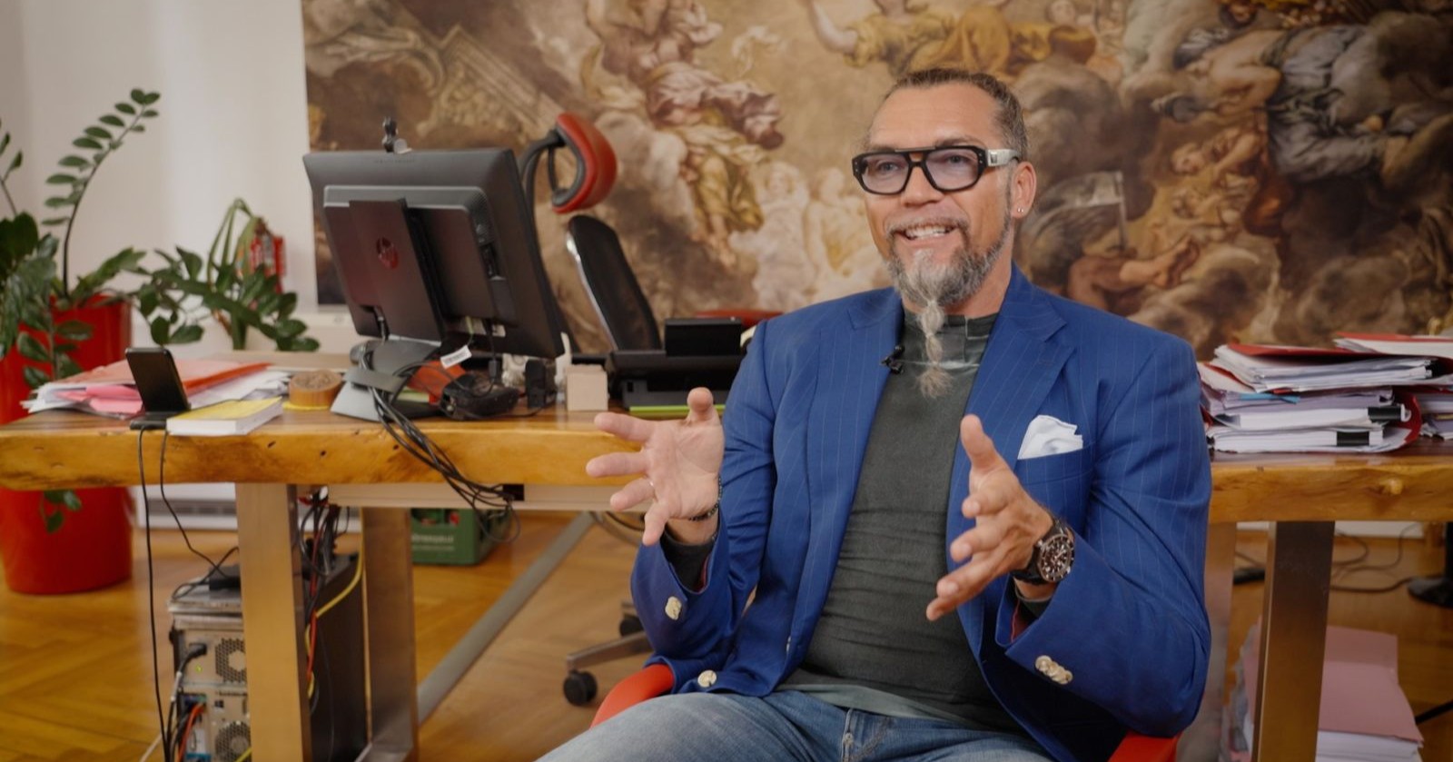 Mann mit blauem Sakko sitzt in Sessel