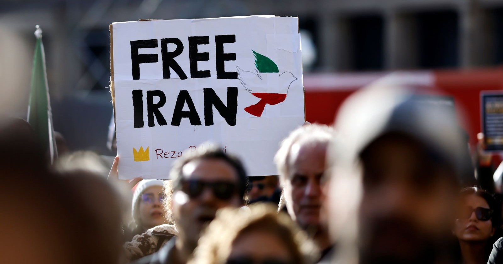 Menschen protestieren mit einem Schild, auf dem „Free Iran“ und eine Taube in den iranischen Nationalfarben zu sehen sind.