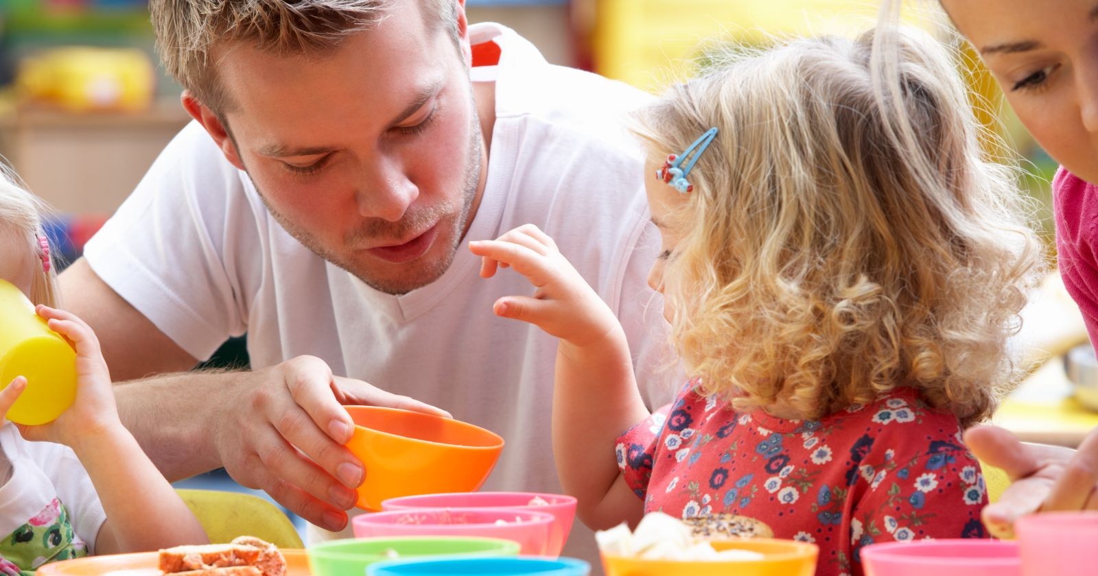 Kindergärtner spricht mit Kind am Tisch