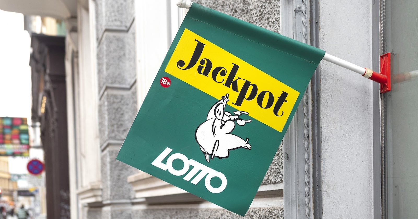 Grüne Lotto-Fahne vor einer Trafik mit dem Lotto-Schwein als Markenzeichen