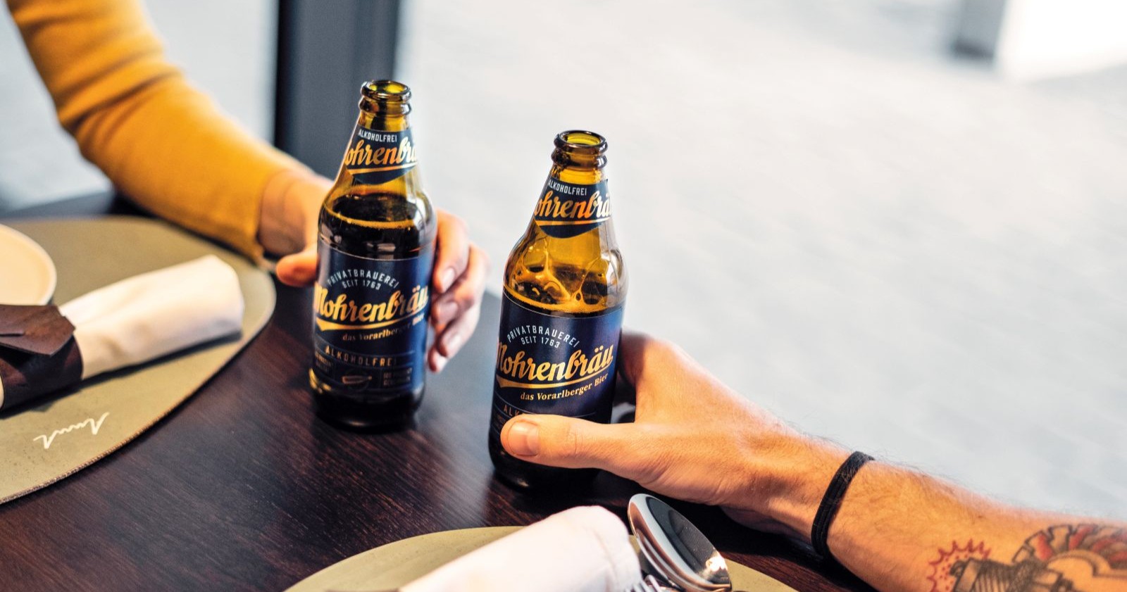 Zwei Menschen stoßen mit einer Flasche alkohlfreiem Mohrenbräu-Bier an.