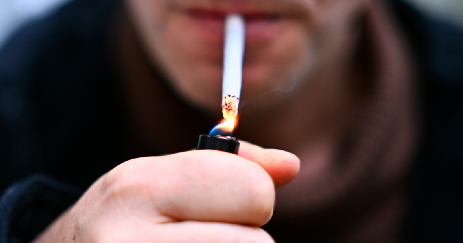 Mann der eine Zigarette anzündet.