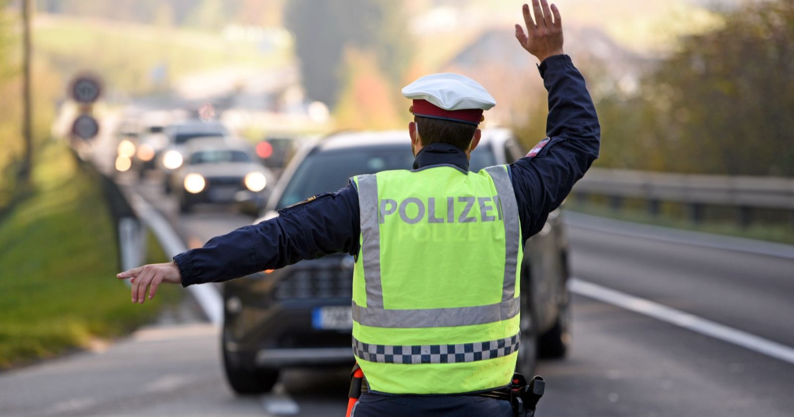 Ein Polizist der Autos aus dem Verkehr zur Umleitung hinweist.