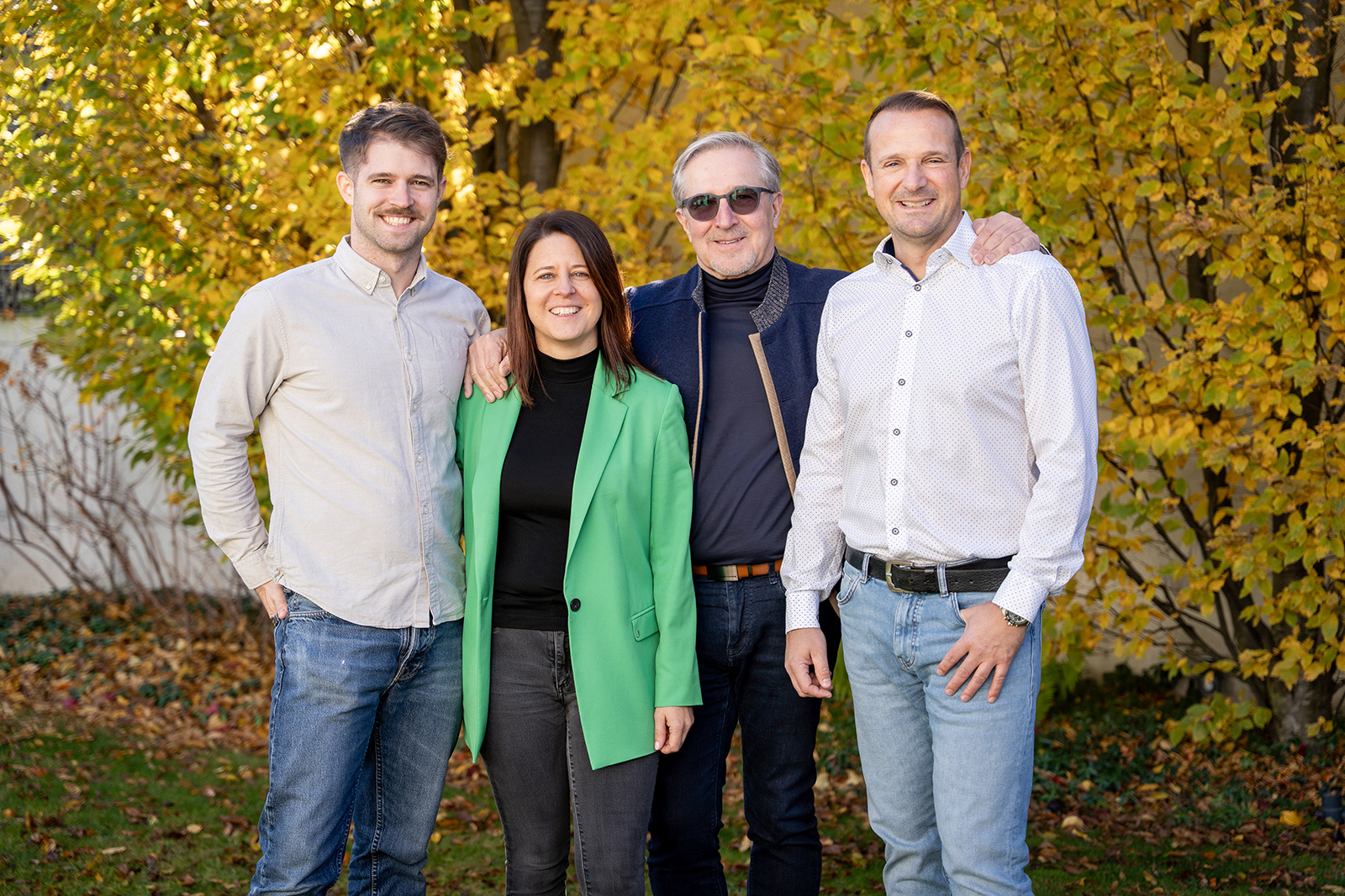 Drei Frauen und ein Man posieren für ein Gruppenfoto vor herbstlicher Kulisse | Credit: baderbau