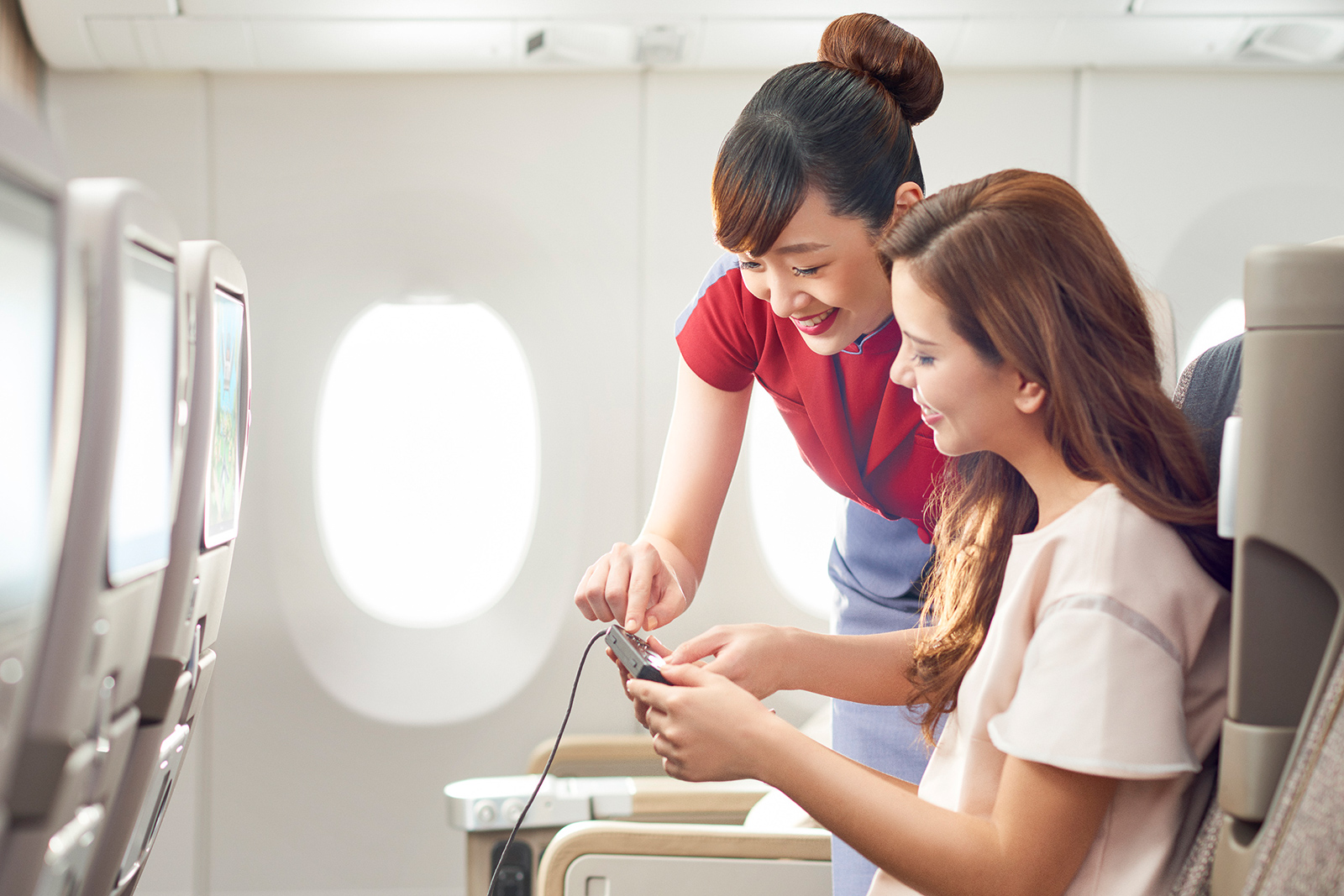 Stewardess hilft weiblichem Fluggast beim Entertainment-Programm | Credit: China Airlines