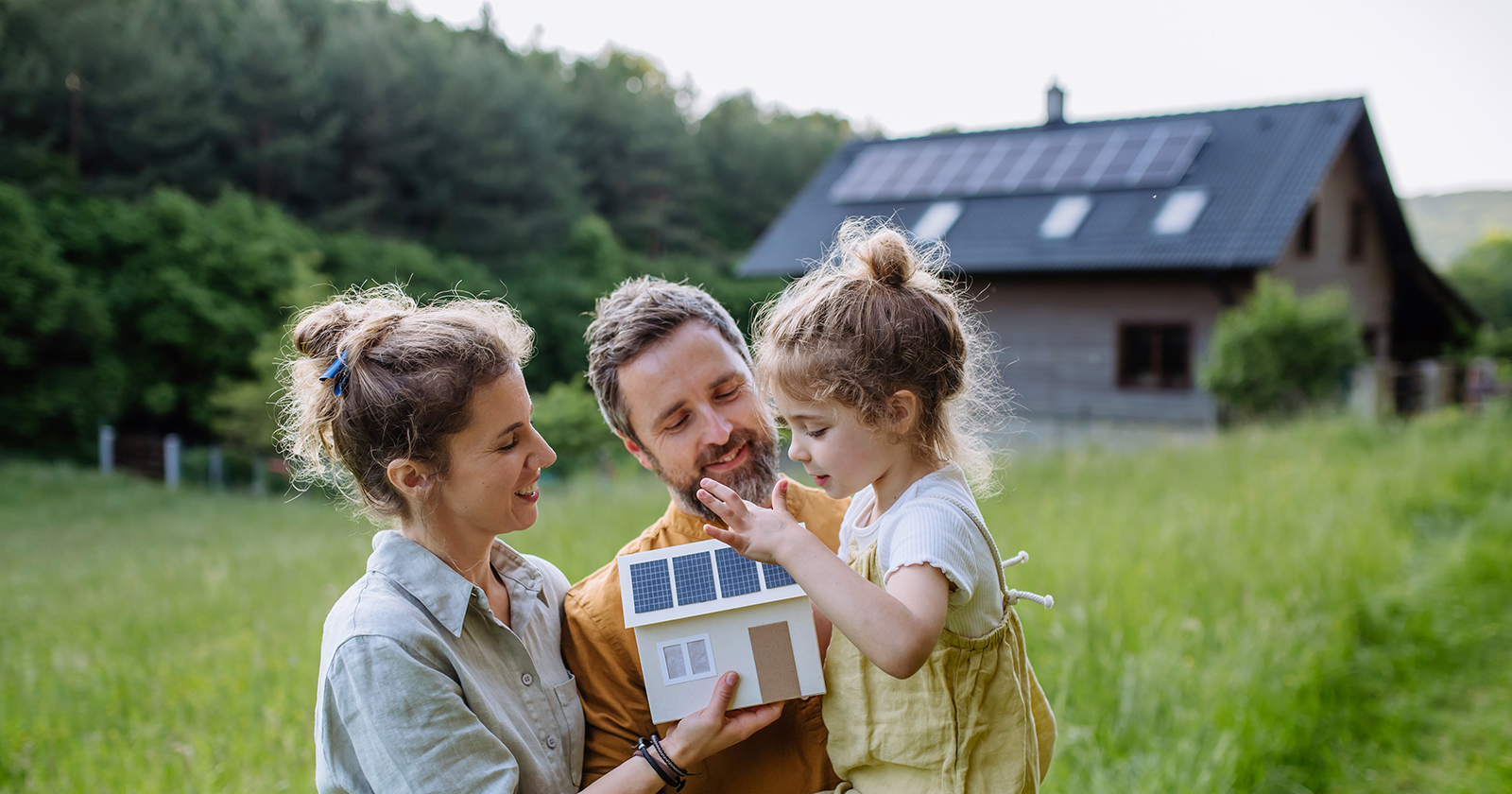 Junges Elternpaar mit ihrer kleinen Tochter vor ihrem Haus | Credit: iStock.com/Halfpoint